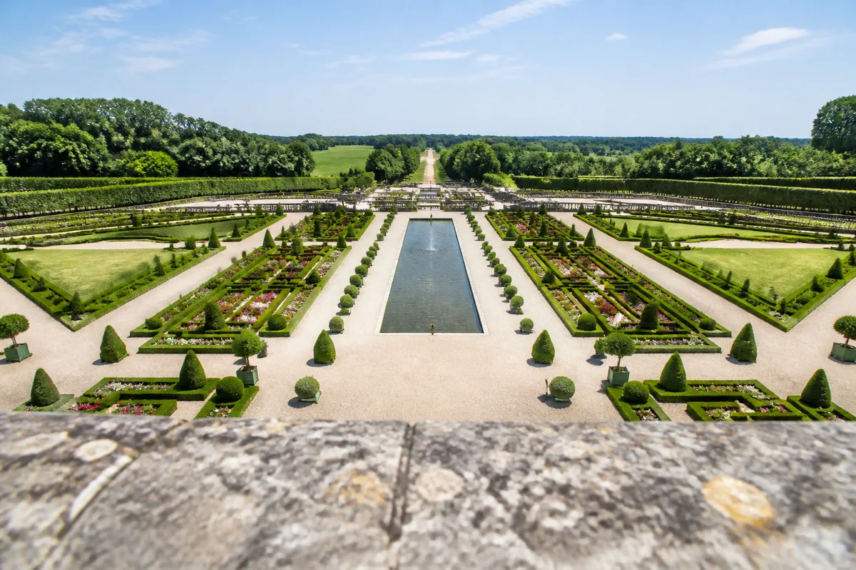 Jardins à la française géométriques photographiés en plongée depuis une terrasse de pierre
